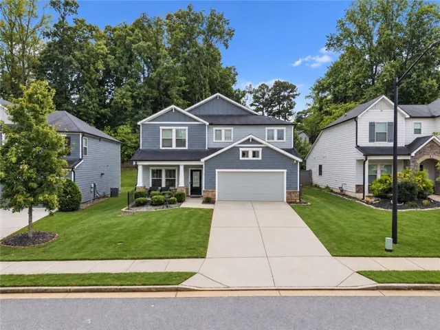 Two-story residence featuring a gray exterior with white trim, a covered front porch, an attached garage, and a concrete driveway