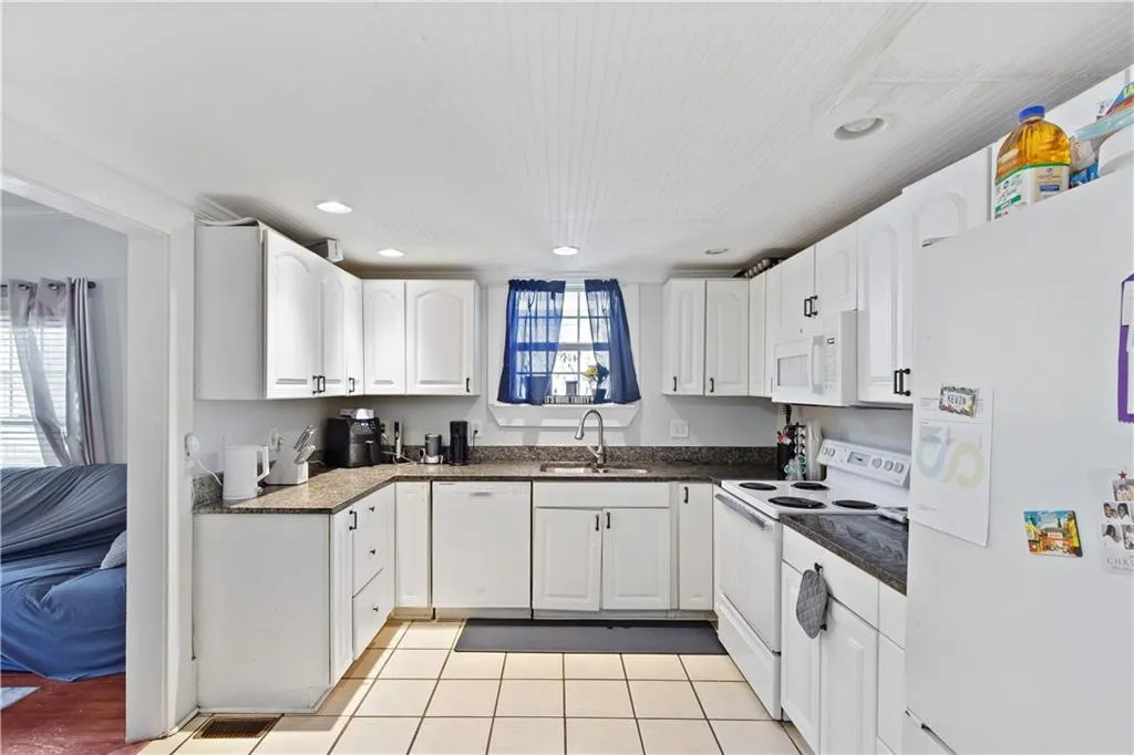Kitchen featuring white cabinetry, a wealth of natural light, and white appliances