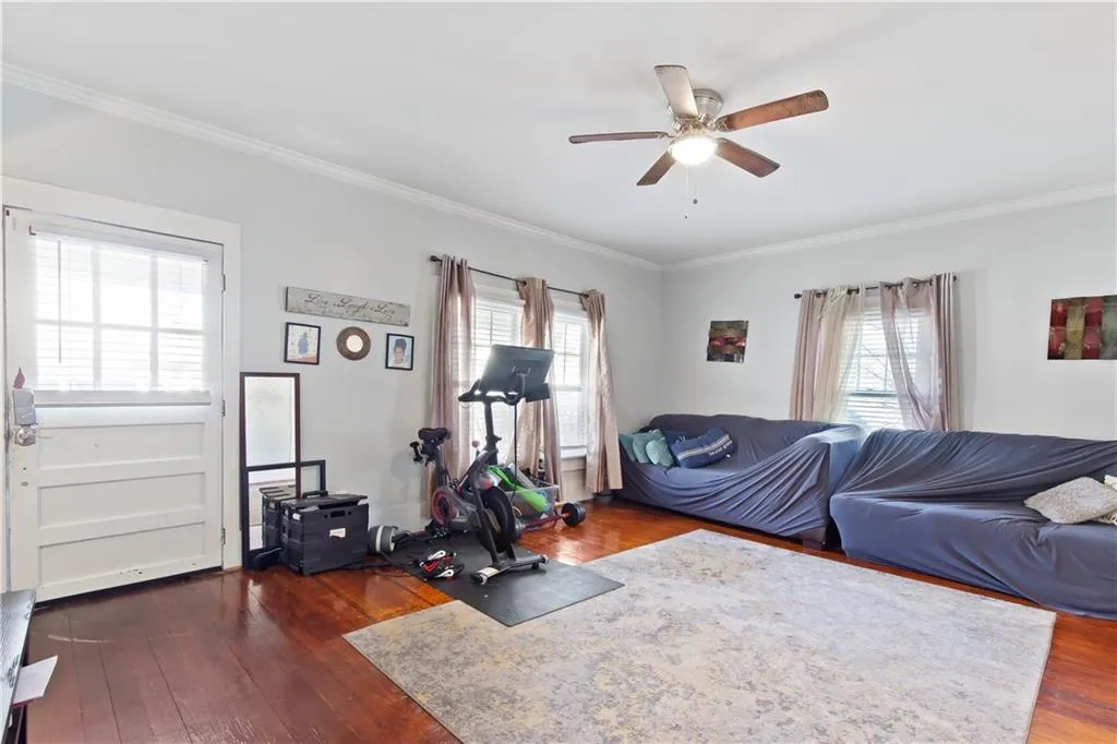 Exercise room featuring ornamental molding, dark wood-type flooring, and ceiling fan