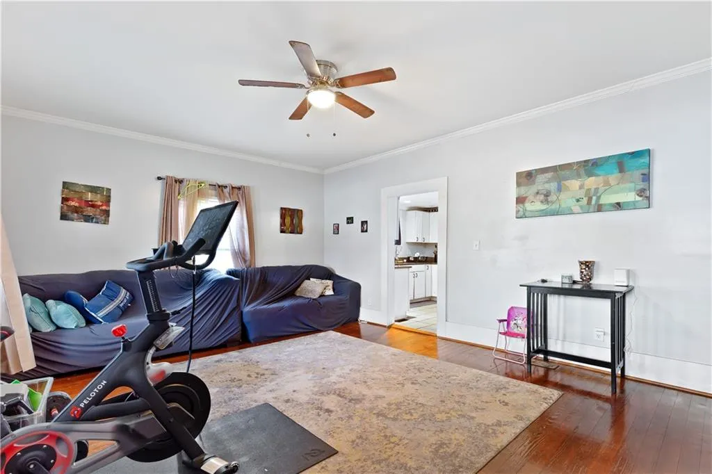 Exercise area featuring ornamental molding, dark wood-type flooring, and ceiling fan