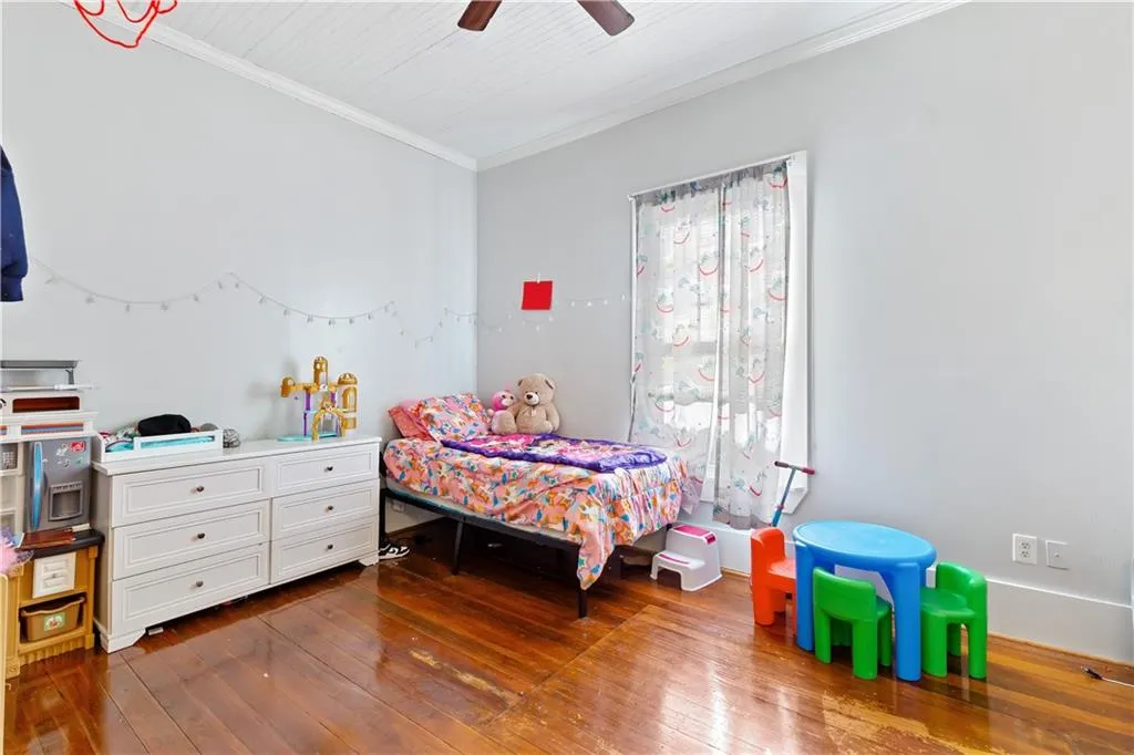 Bedroom featuring dark wood-type flooring, crown molding, and ceiling fan