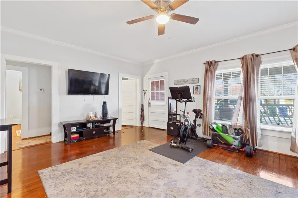 Workout room featuring dark hardwood / wood-style flooring, crown molding, and ceiling fan