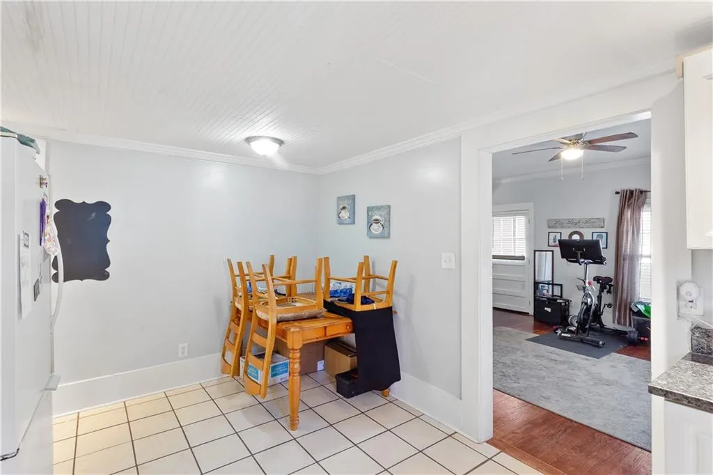 Tiled dining room with ornamental molding and ceiling fan