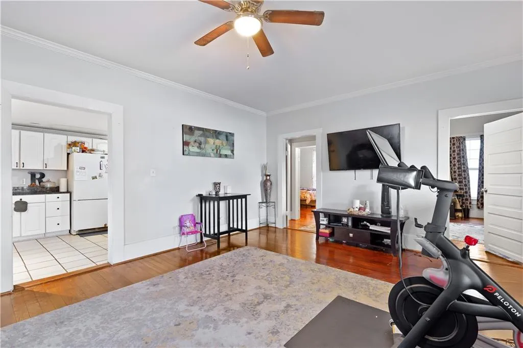 Workout area featuring ceiling fan, ornamental molding, and light tile floors