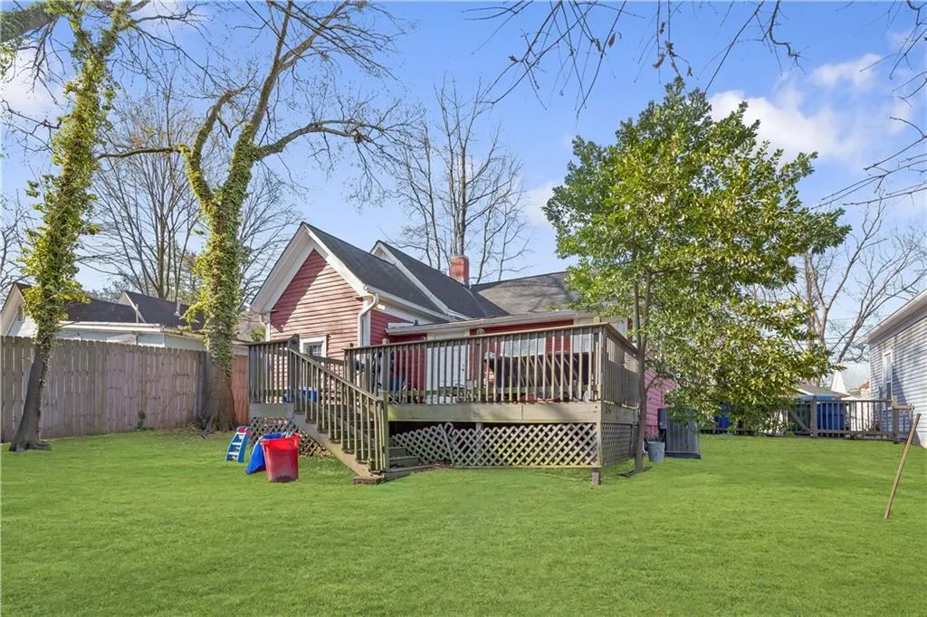 Back of house with a wooden deck and a lawn