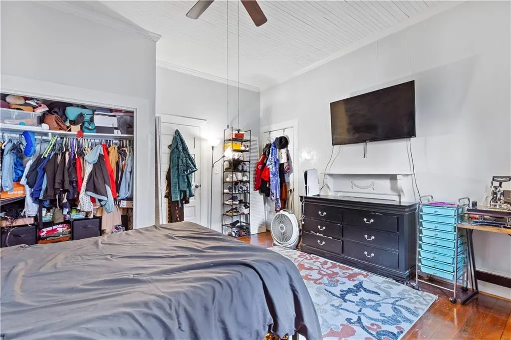 Bedroom featuring crown molding, a closet, dark wood-type flooring, and ceiling fan