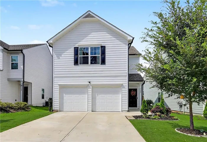 Two-story exterior with white siding, a two-car garage, and a concrete driveway