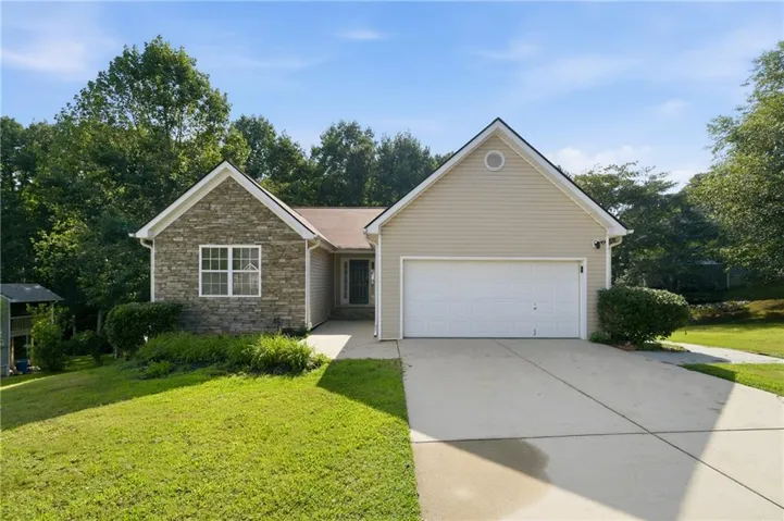 Stone veneer and siding exterior with an attached garage, concrete driveway, and front walk