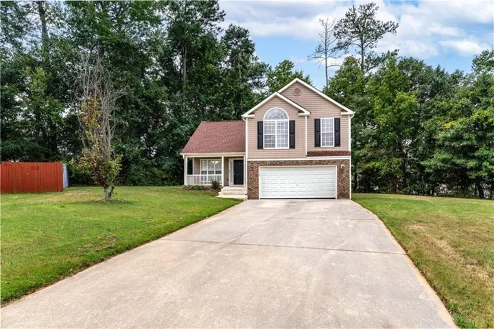 View of front of property featuring driveway, a front lawn, a garage, and covered porch