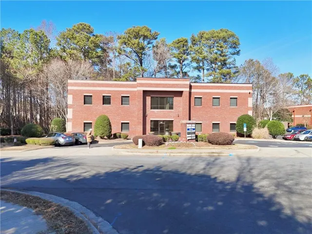 Brick commercial building featuring multiple windows and a central glass entrance