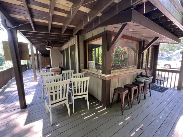 Expansive wood-finish deck with a built-in outdoor bar, equipped with a pass-through window and integrated lighting