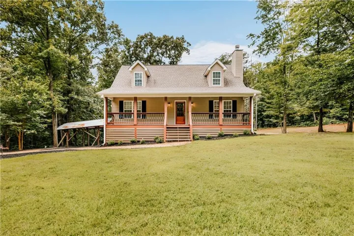 Craftsman-style home featuring a covered front porch with a wood railing, dormer windows, and a prominent chimney
