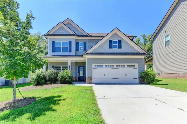 Two-story home featuring a two-car garage, stone accents, gabled rooflines, and a covered porch