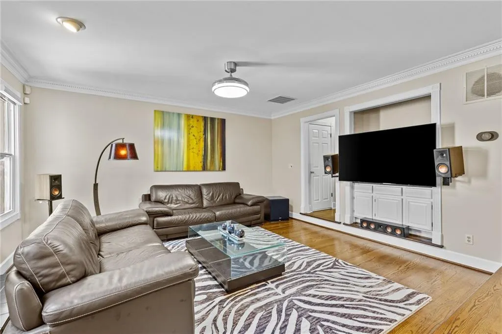 Living area with crown molding and light wood-style floors
