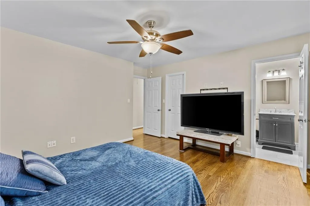 Bedroom featuring light wood-type flooring, a ceiling fan, and ensuite bathroom