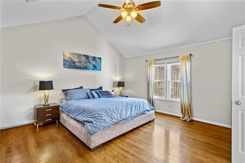Bedroom featuring wood finished floors, a ceiling fan, and a high ceiling