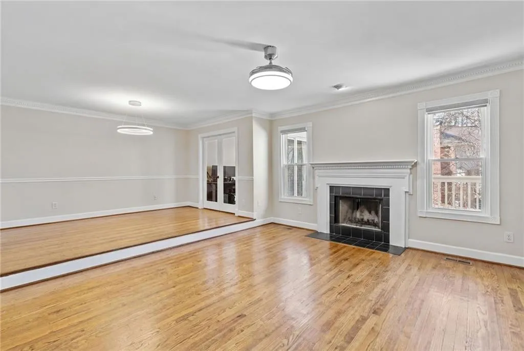 Unfurnished living room with light wood-style floors, ornamental molding, a tiled fireplace, and plenty of natural light