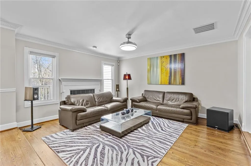 Living area with ornamental molding, light wood-style floors, and a fireplace