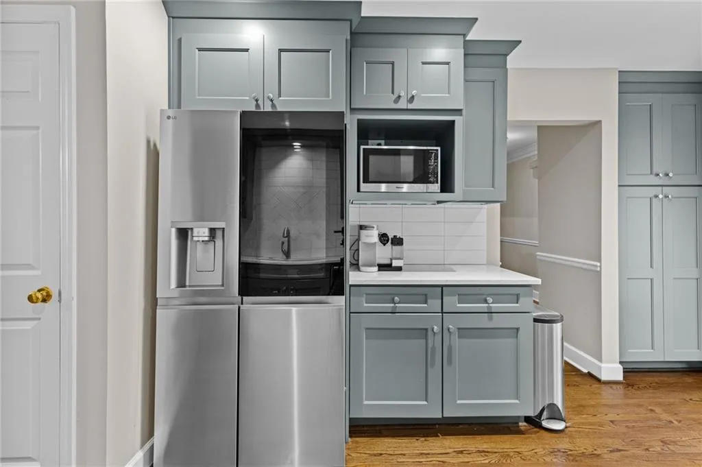 Kitchen featuring stainless steel appliances, light stone countertops, gray cabinets, tasteful backsplash, and light wood-style floors