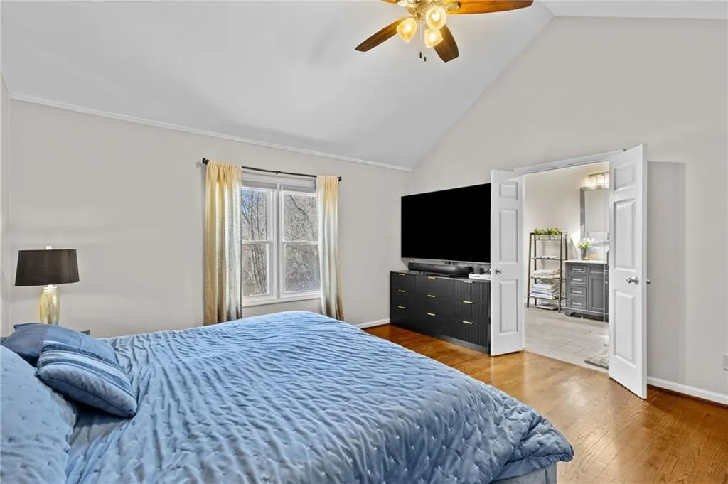 Bedroom with light wood-style floors, vaulted ceiling, and ceiling fan