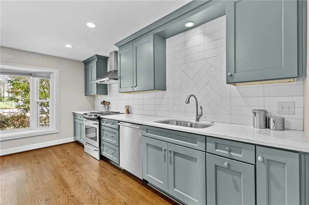 Kitchen with stainless steel appliances, light stone countertops, recessed lighting, light wood-type flooring, and backsplash