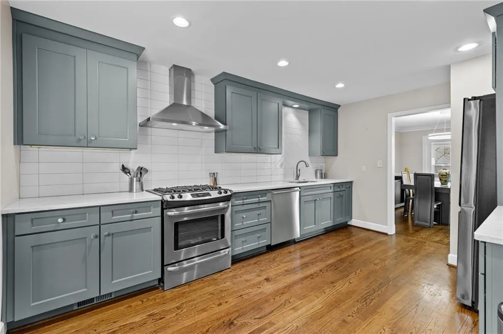 Kitchen featuring stainless steel appliances, light stone counters, dark wood finished floors, backsplash, and recessed lighting