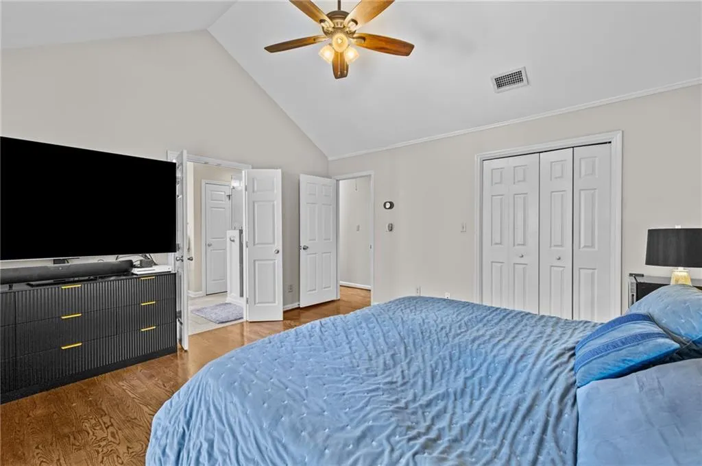 Bedroom featuring wood finished floors, a high ceiling, a ceiling fan, and a closet