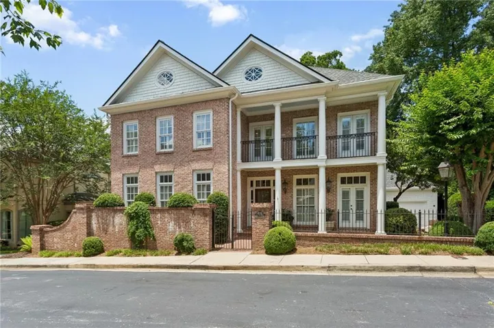 Brick facade residence featuring a double-story porch with white columns and black iron railings