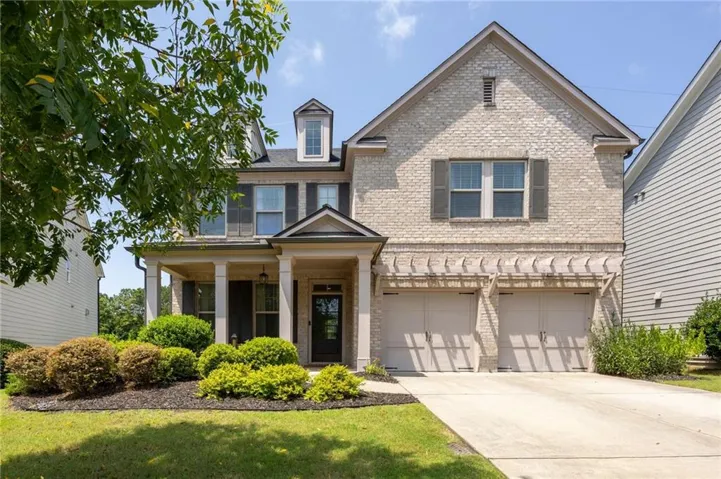 Light brick exterior with a front porch, dormer windows, and a two-car garage