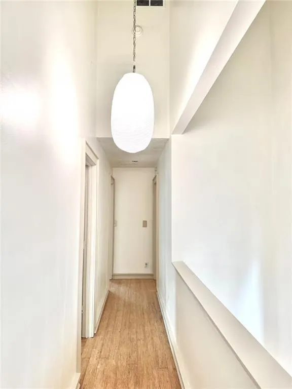Hallway featuring a towering ceiling and light wood-style flooring