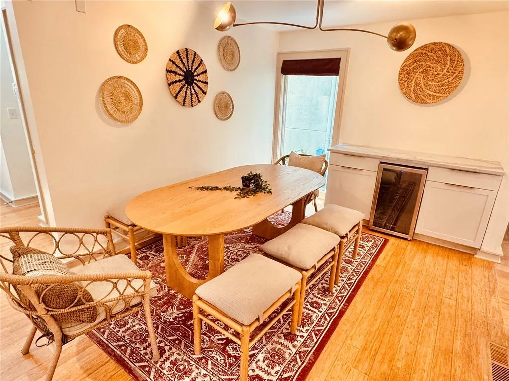 Dining room with light wood-type flooring, wine cooler, and a dry bar