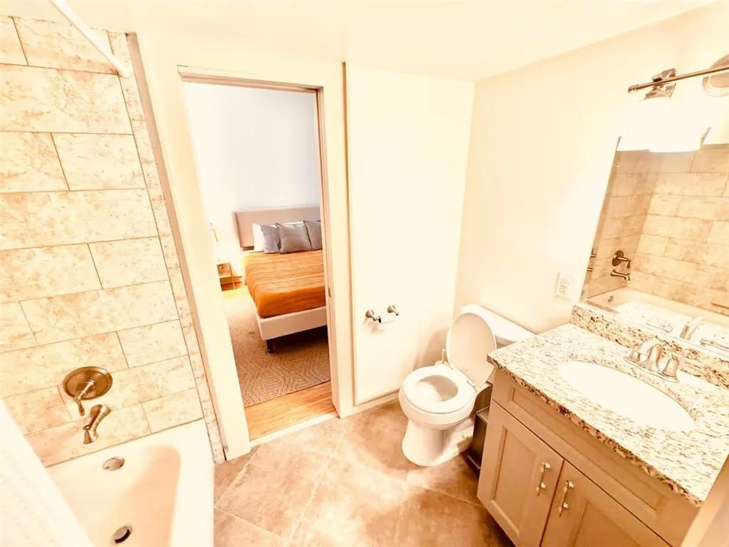 Ensuite bathroom with vanity, shower / tub combination, and tile patterned flooring