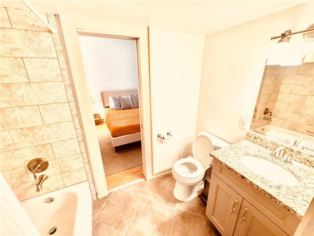 Ensuite bathroom featuring vanity,  shower combination, and tile patterned flooring