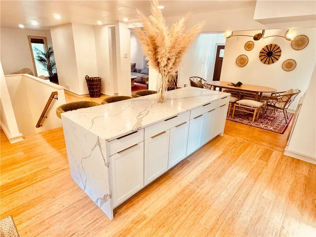 Kitchen featuring white cabinetry, light wood finished floors, and light stone counters