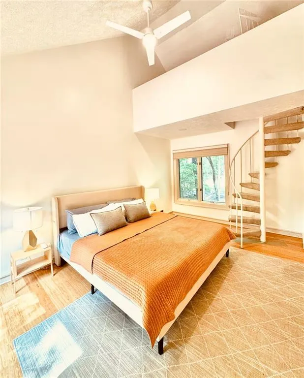 Bedroom featuring wood finished floors, a textured ceiling, ceiling fan, and high vaulted ceiling