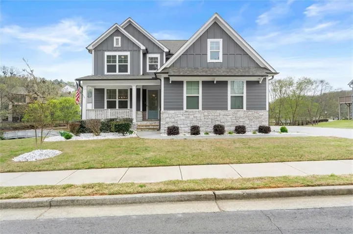 Craftsman inspired home featuring a covered front porch, board and batten and stone siding.