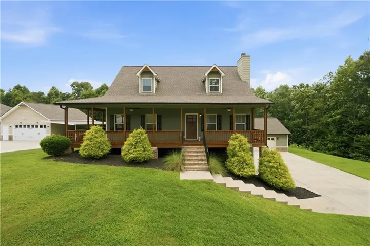 Front facade featuring a covered porch, dormer windows, and a multi-car garage structure