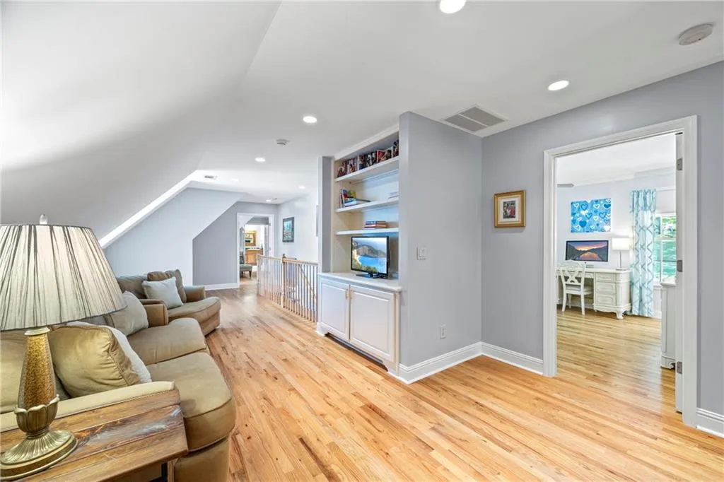 Living area with lofted ceiling, baseboards, visible vents, and light wood-style floors