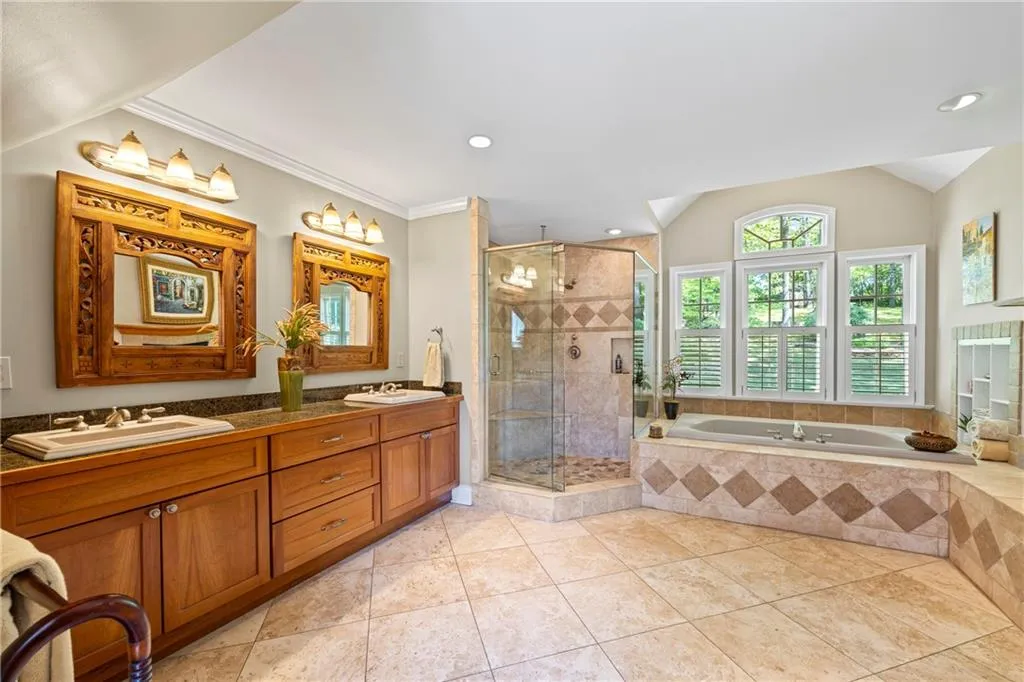 Bathroom with a bath, vaulted ceiling, a sink, and a stall shower