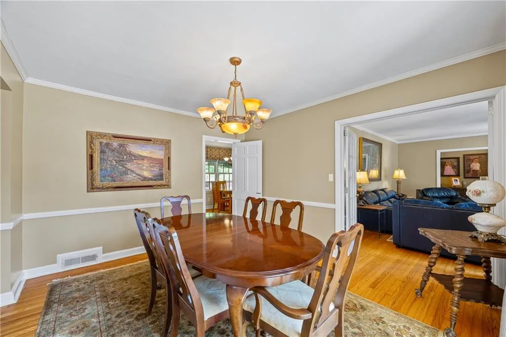 Dining space featuring light wood finished floors, visible vents, a chandelier, and ornamental molding