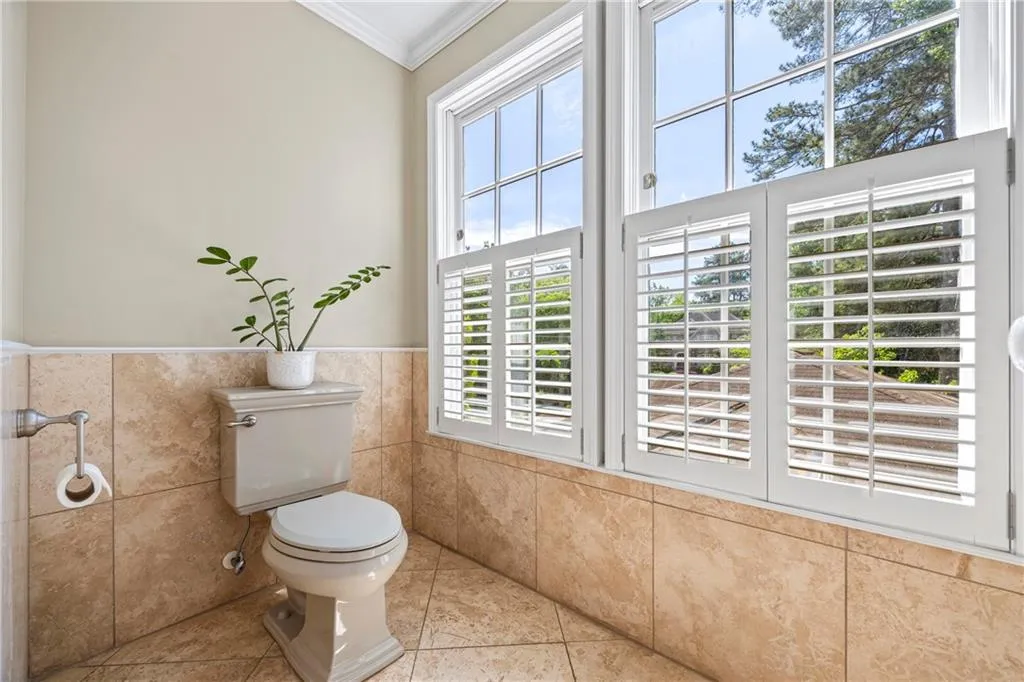 Bathroom featuring crown molding, tile walls, a wainscoted wall, toilet, and tile patterned flooring