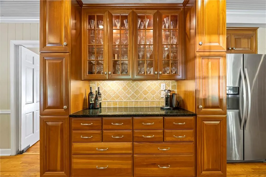 Bar with backsplash, a dry bar, light wood-type flooring, and stainless steel fridge
