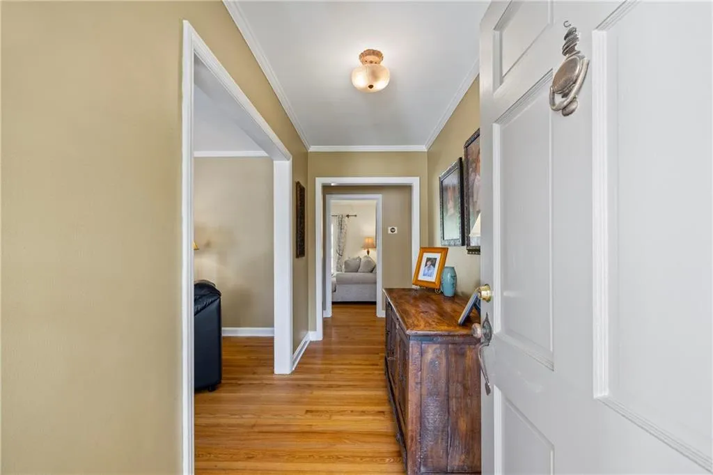 Hall featuring baseboards, crown molding, and light wood-style flooring