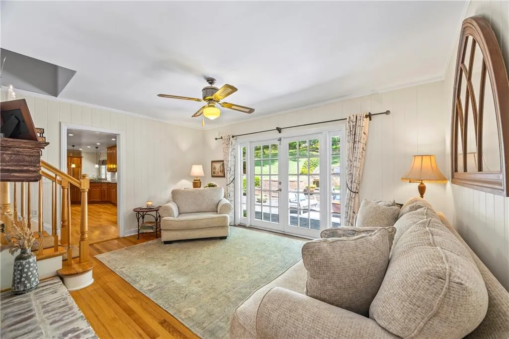 Living room with wood walls, wood finished floors, stairs, ceiling fan, and crown molding