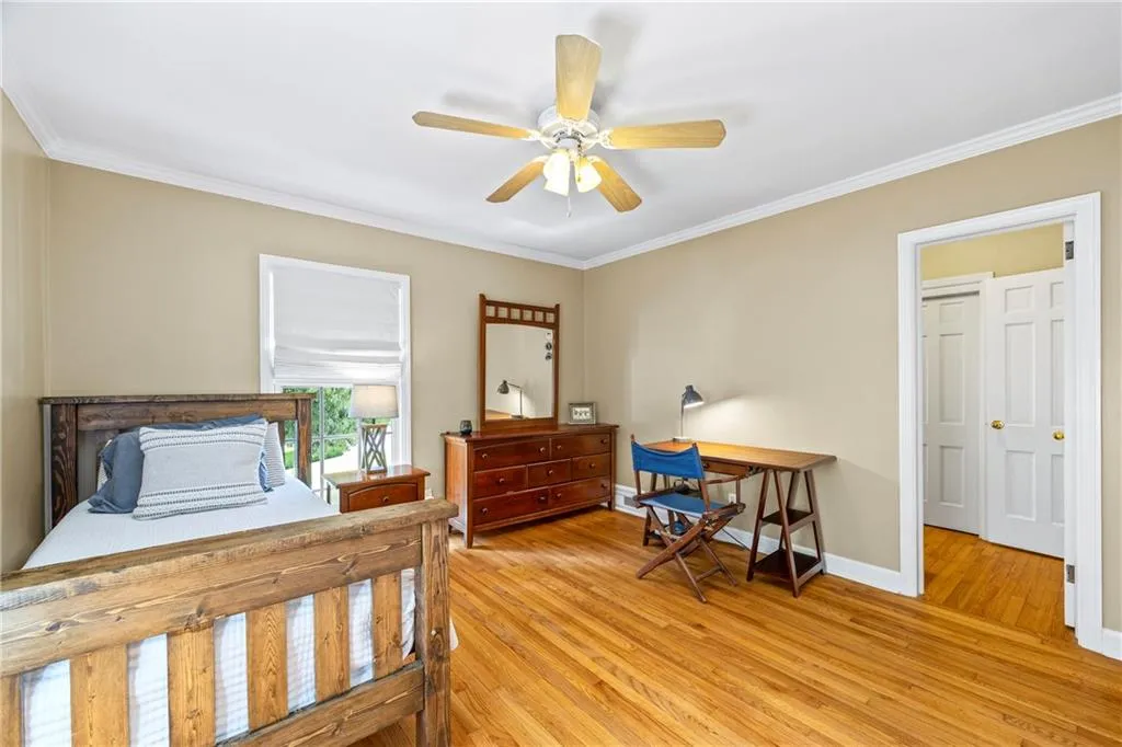 Bedroom with a ceiling fan, baseboards, ornamental molding, and light wood finished floors