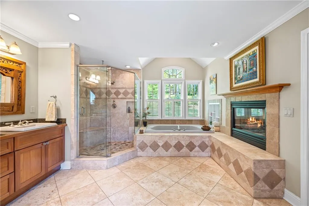 Bathroom with tile patterned flooring, a shower stall, a garden tub, vanity, and a fireplace