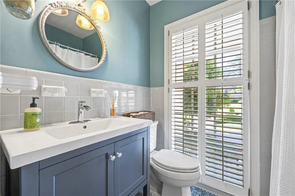 Full bath featuring tile walls, toilet, vanity, and a shower with curtain