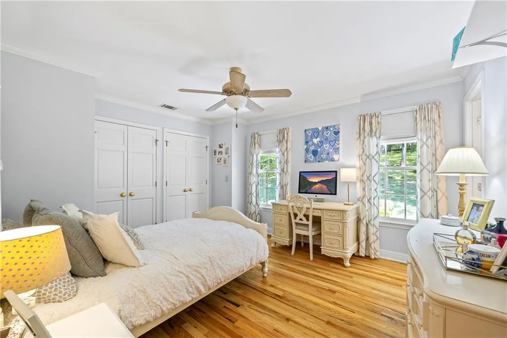 Bedroom featuring crown molding, multiple closets, light wood-style floors, and multiple windows