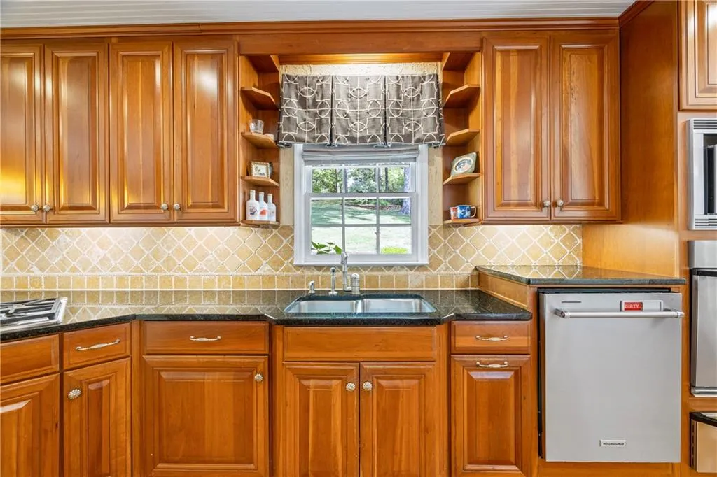 Kitchen featuring open shelves, brown cabinetry, stainless steel appliances, and a sink