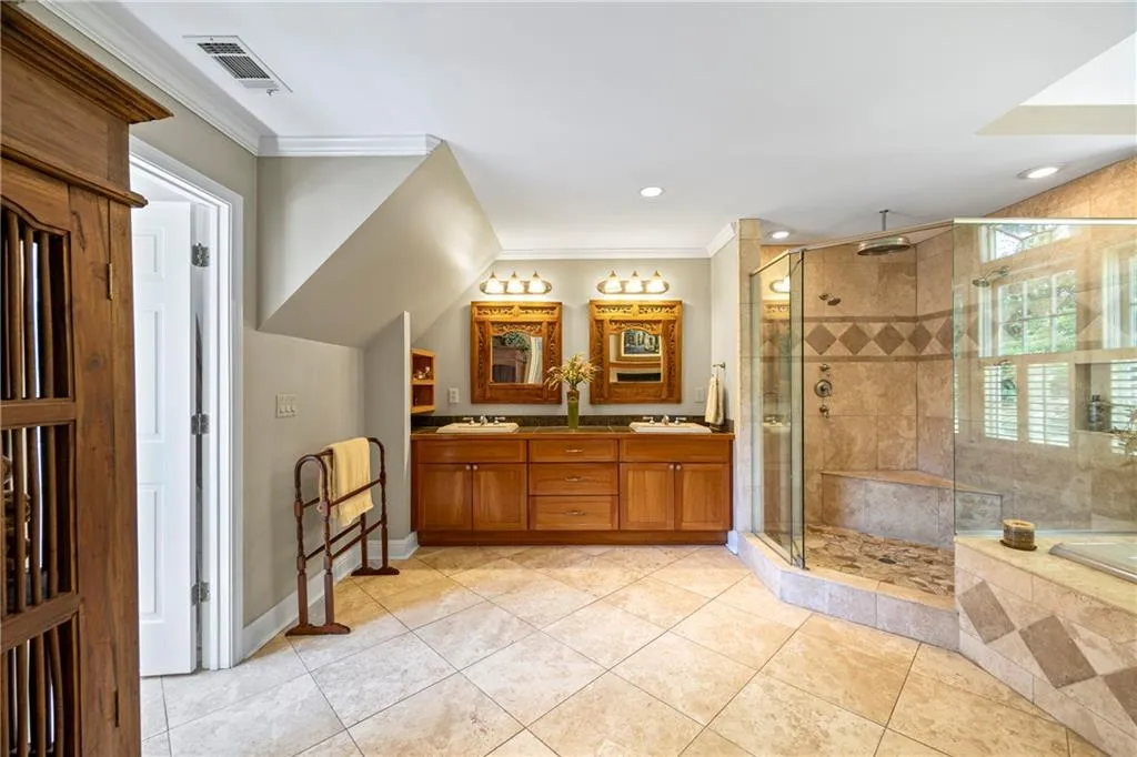 Bathroom featuring crown molding, a sink, visible vents, and a stall shower